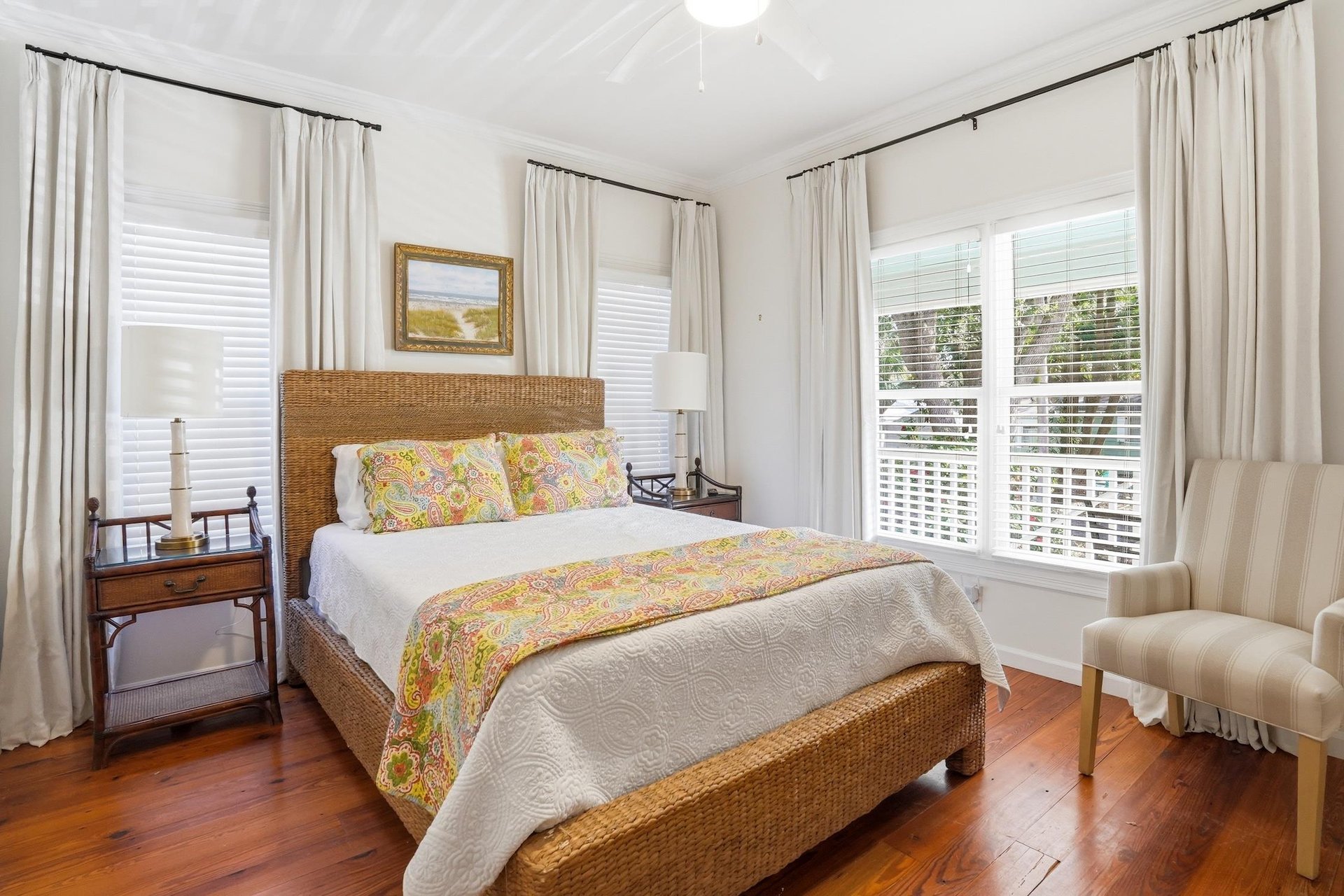 Main floor queen bedroom with hardwood floors and corner windows bringing in natural light.