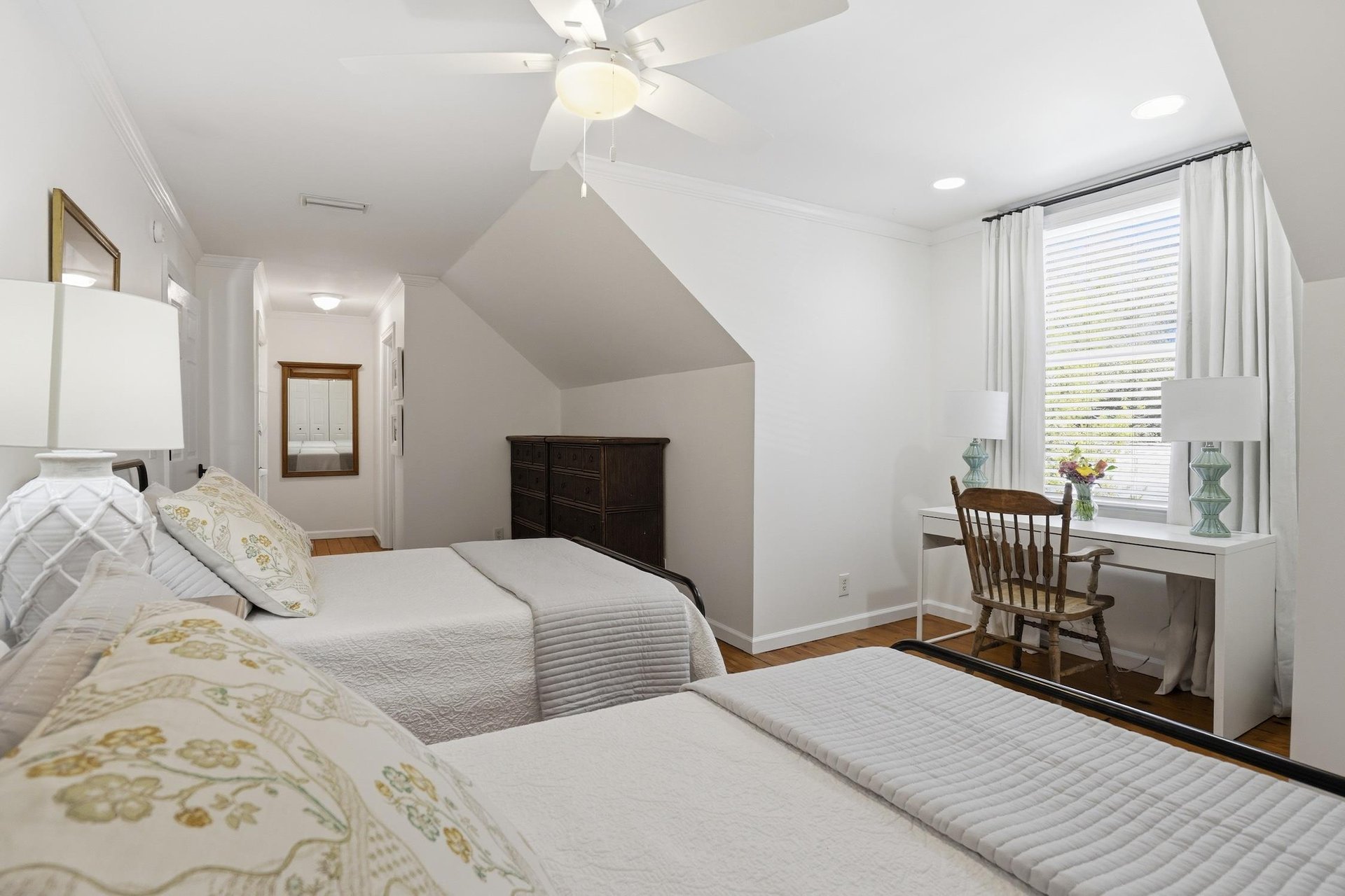 Another look at the upstairs twodouble bedroom with the desk and path toward its attached ensuite bathroom.