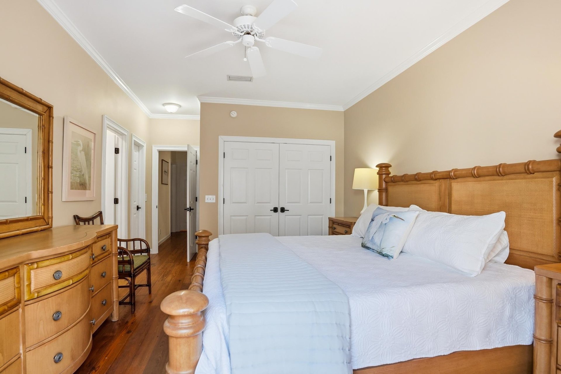 Second view of the main floor king primary suite showing the bed layout, hardwood floors, and easy mainlevel access.
