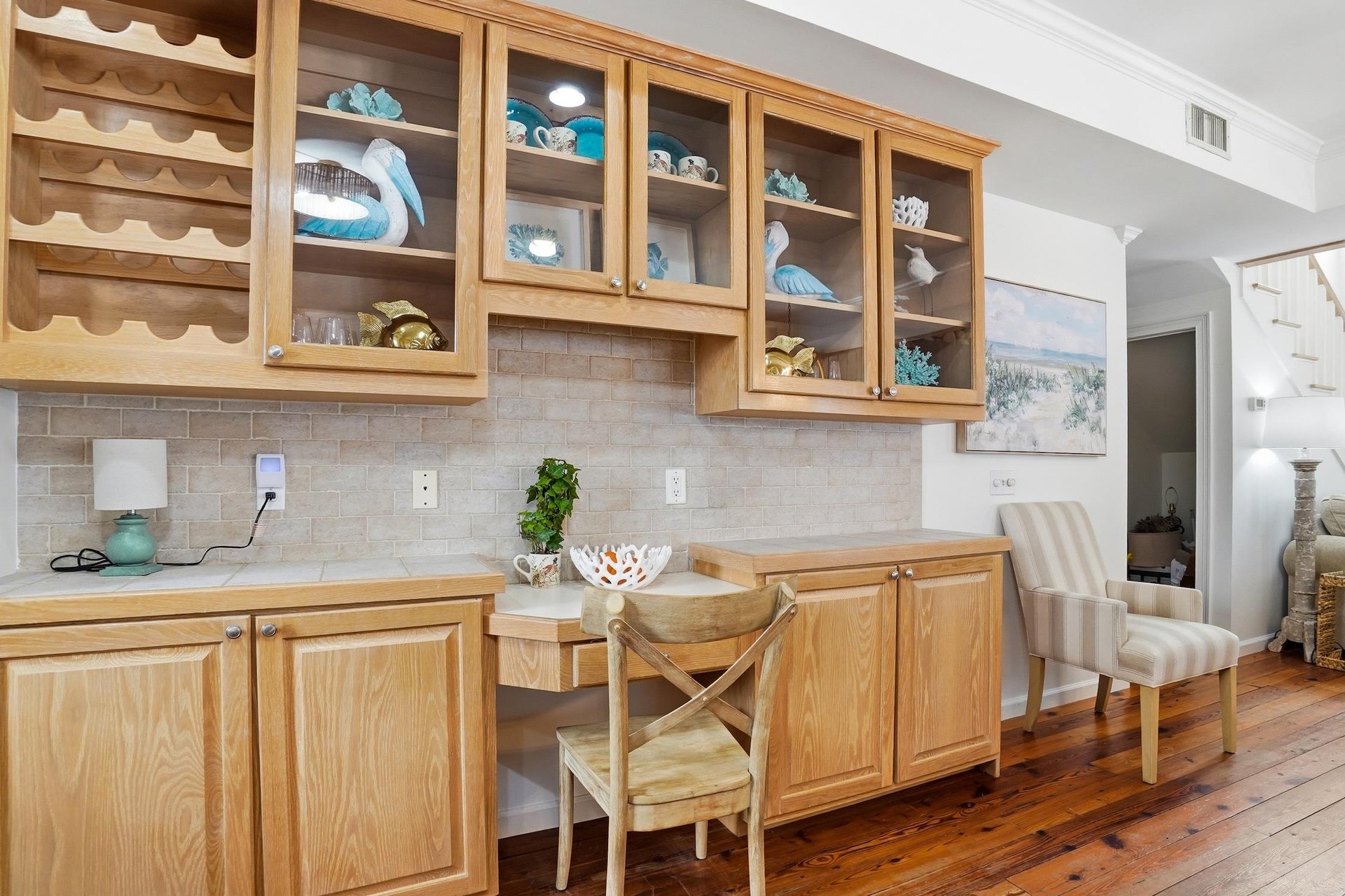 Builtin cabinet with glassfront storage, wine rack, and a small desk nook near the main living area.