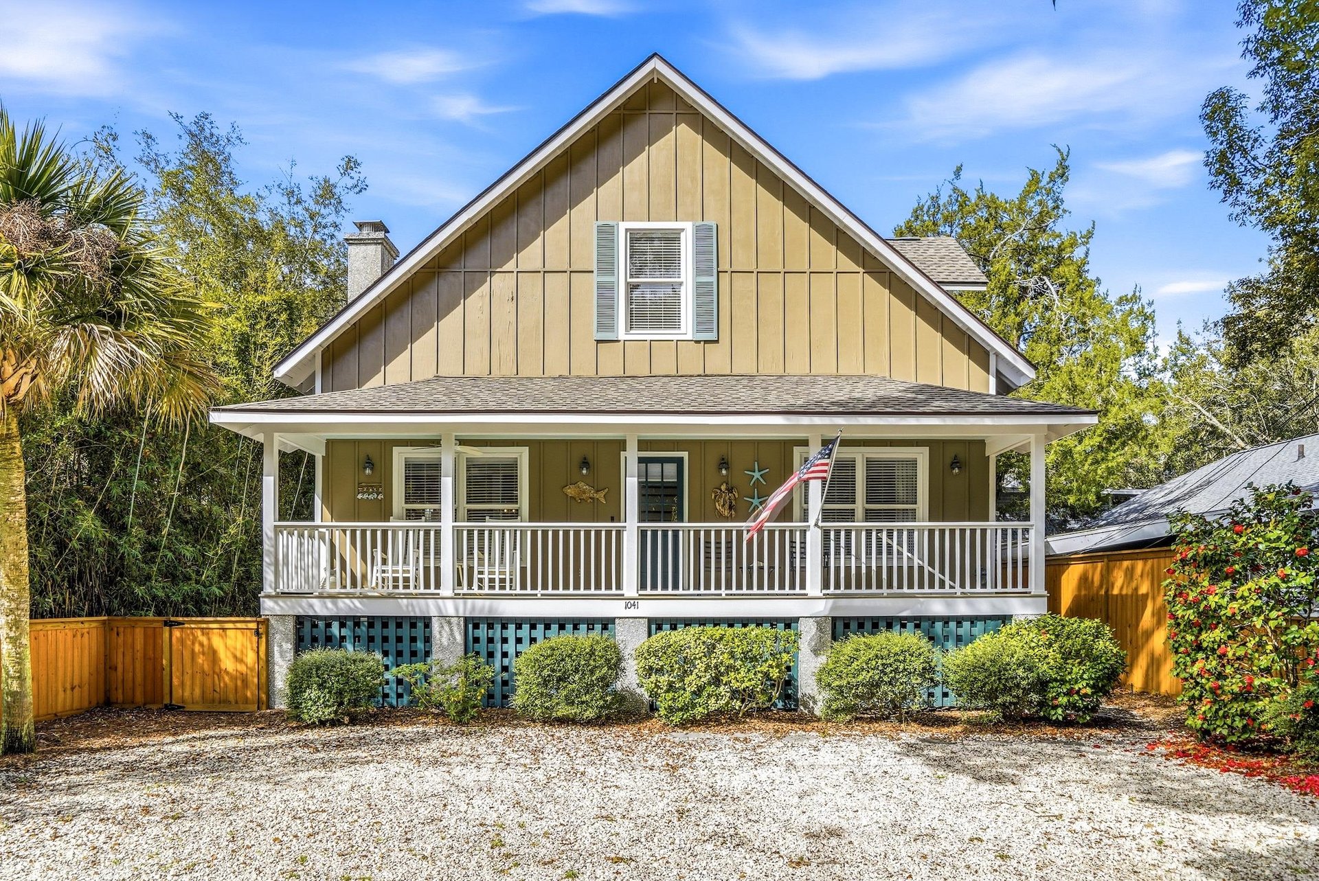 Front exterior view with gravel drive and parking beneath and beside the elevated cottage.