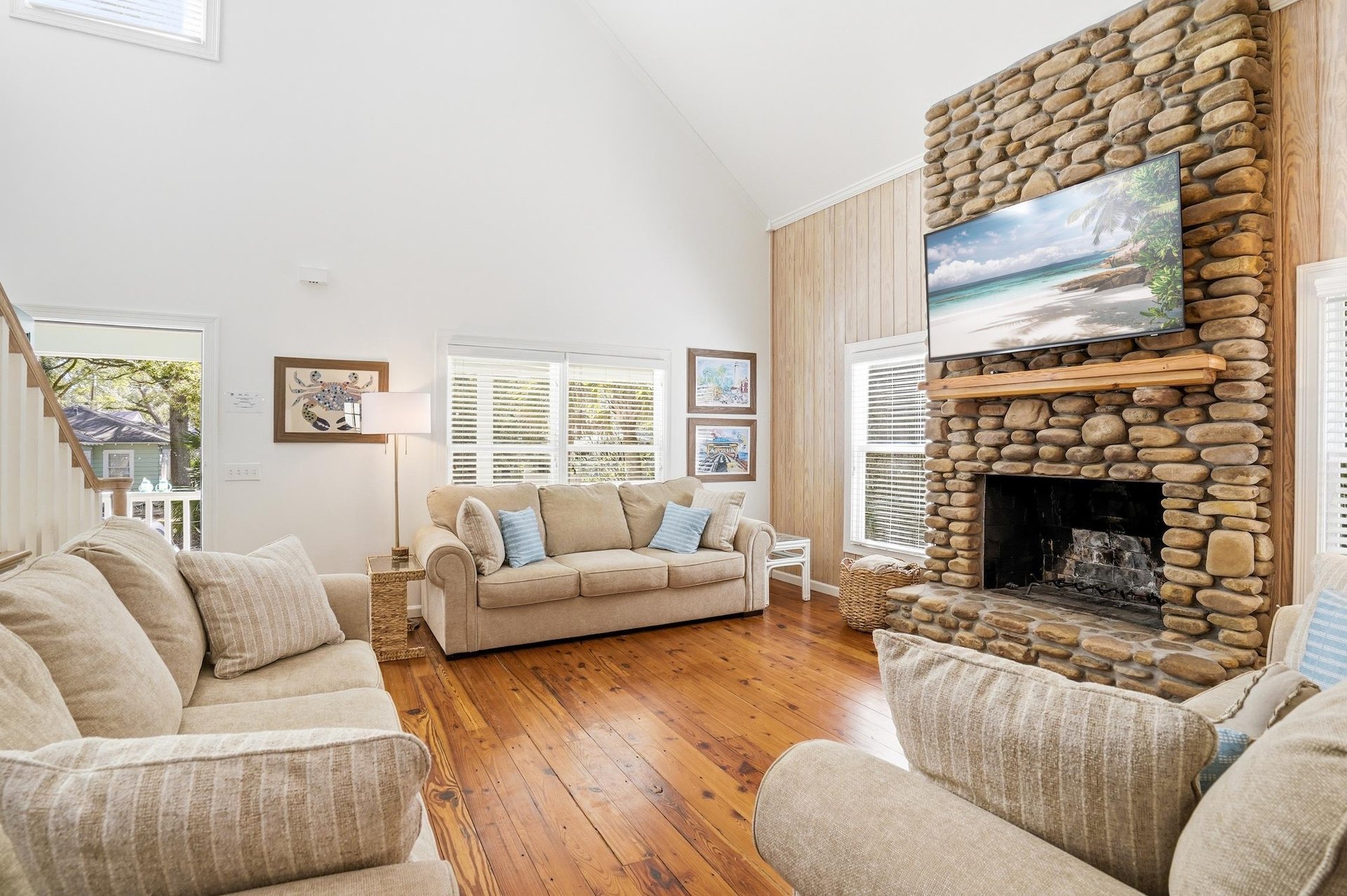 Main living room centered around the fullheight stone fireplace, with hardwood floors and comfortable gathering space.
