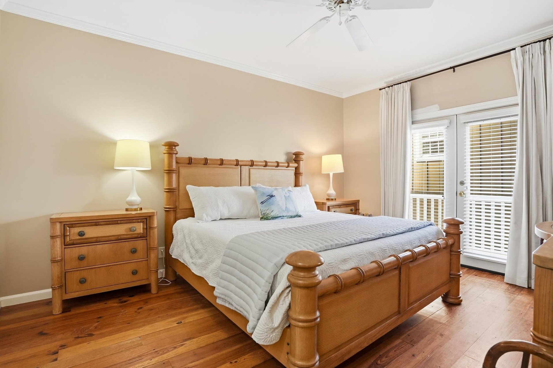 Main floor king primary suite with French doors opening toward the covered balcony.
