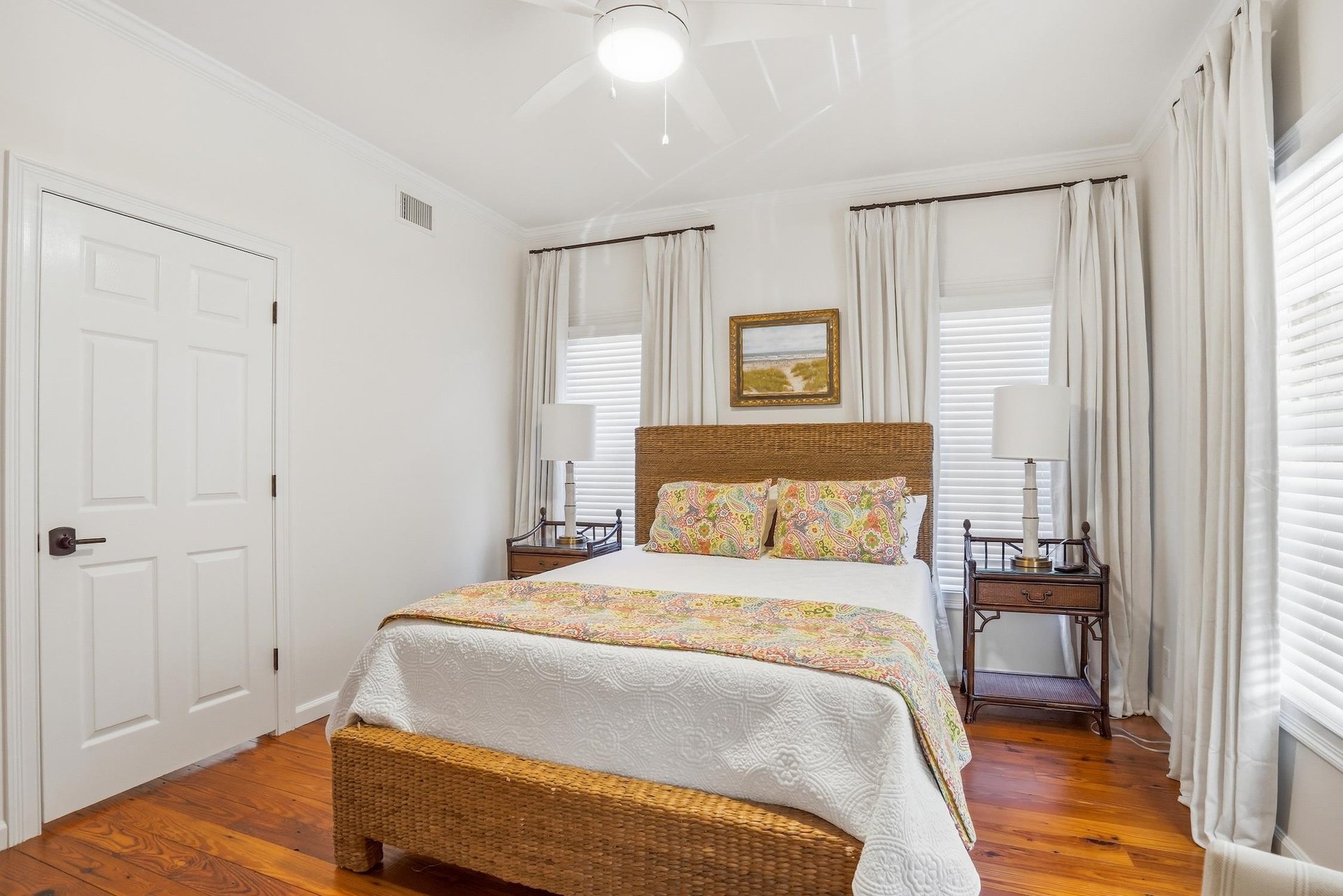 Alternate view of the main floor queen bedroom with natural light and hardwood flooring.