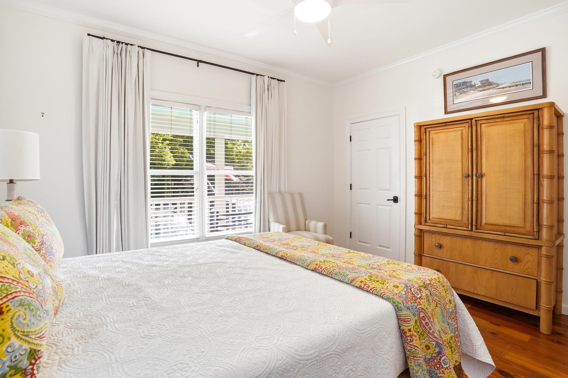 Main floor queen bedroom with hardwood floors and a large window bringing in natural light.