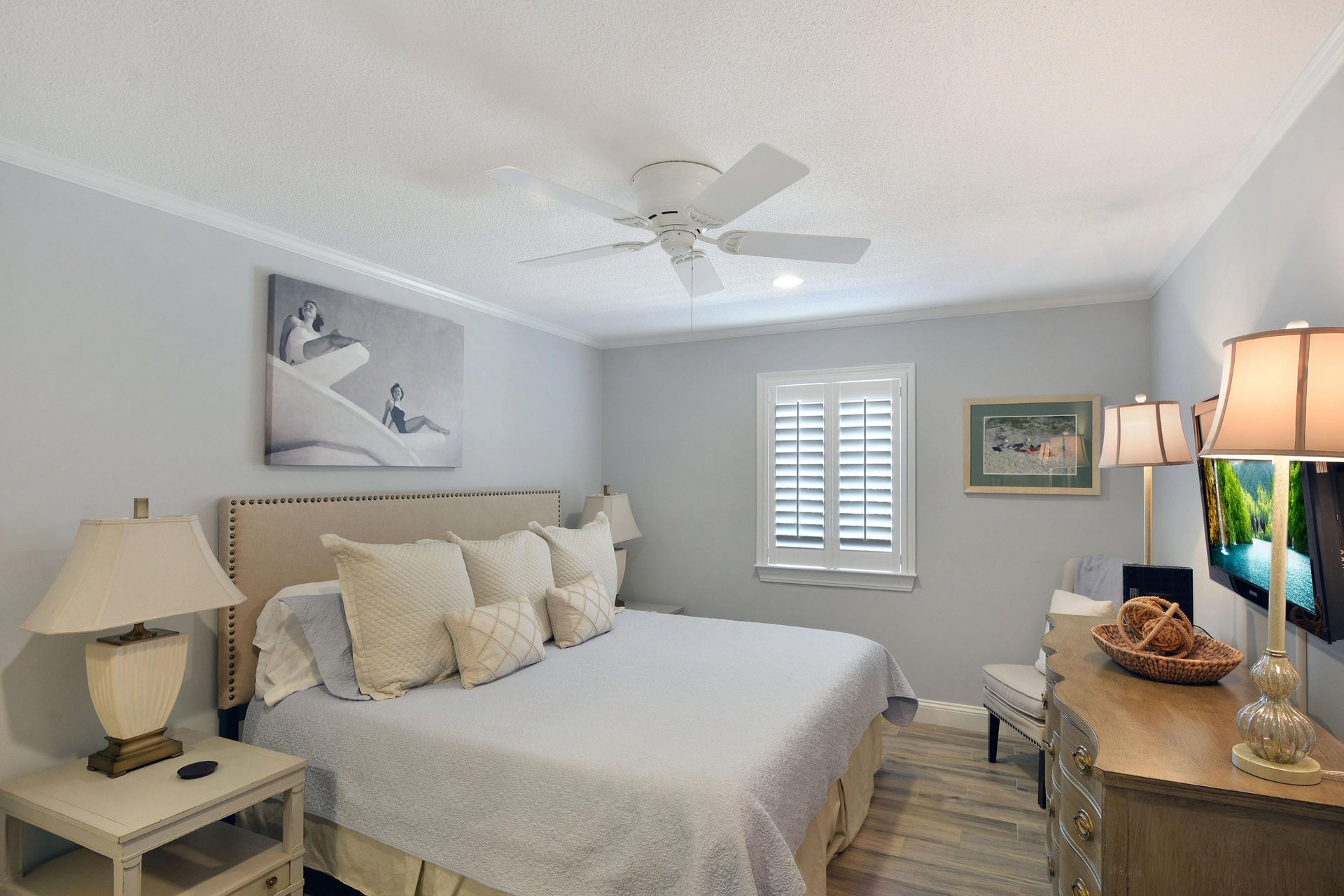 Primary bedroom with king bed, TV, blackout shutters, and ensuite bathroom access.