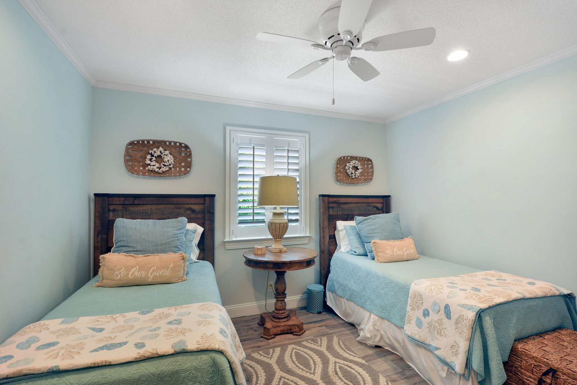 Guest bedroom with two twin beds, ceiling fan, shutters, and hall bathroom access.