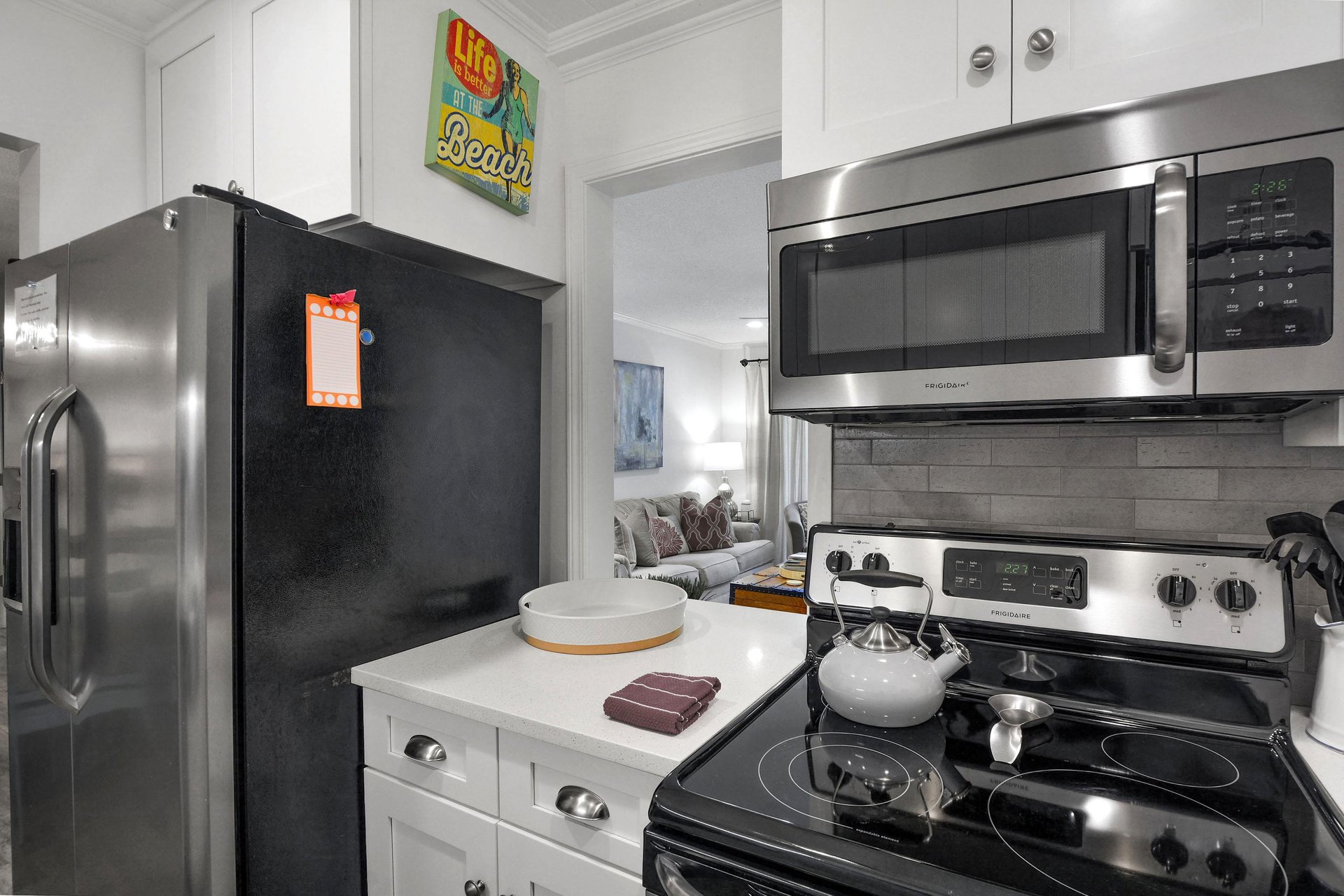 Kitchen angle showing fullsize appliances, microwave, refrigerator, and counter space.
