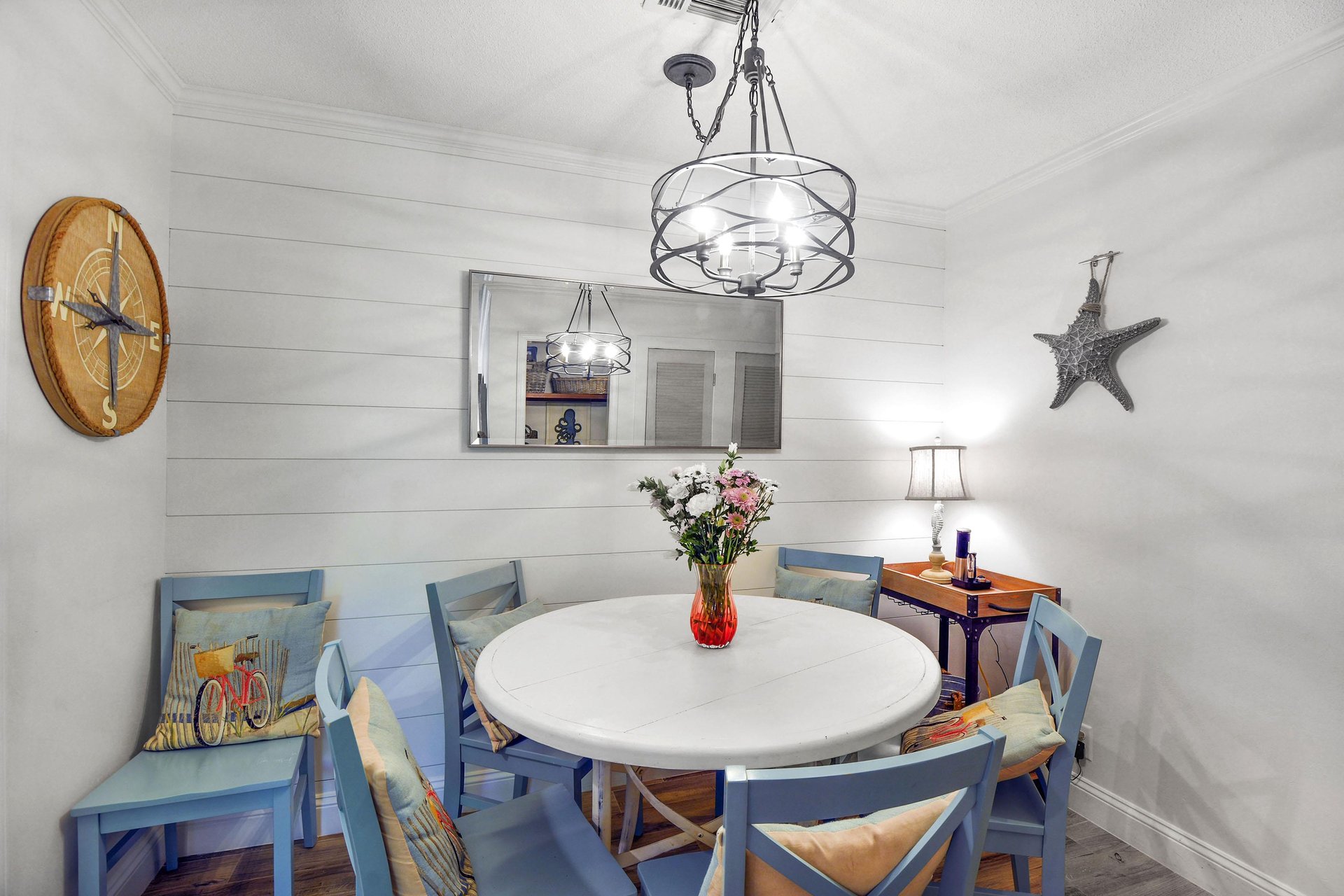 Dining nook with round table, shiplap wall, pendant light, and easy kitchen access.