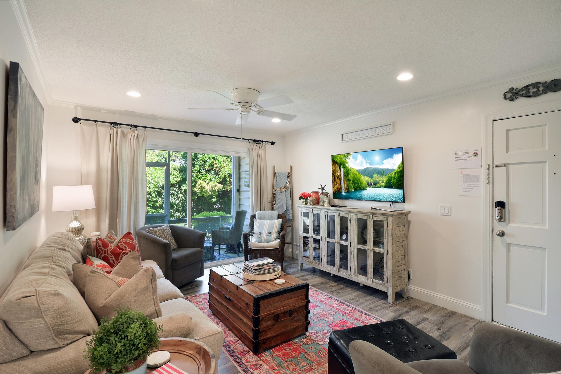 Living room view from the entry, with sofa seating, smart TV, and patio doors.