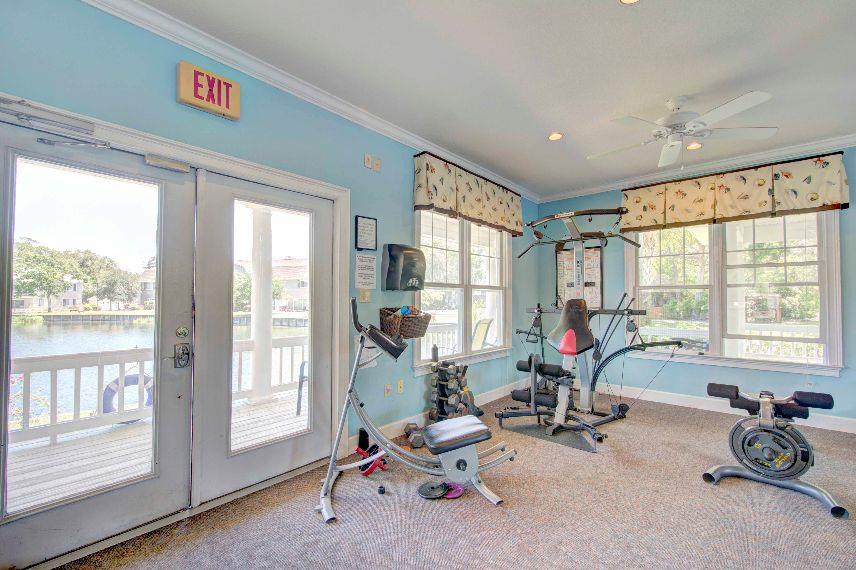 Fitness room angle showing cardio equipment, windows, and the lake outside.