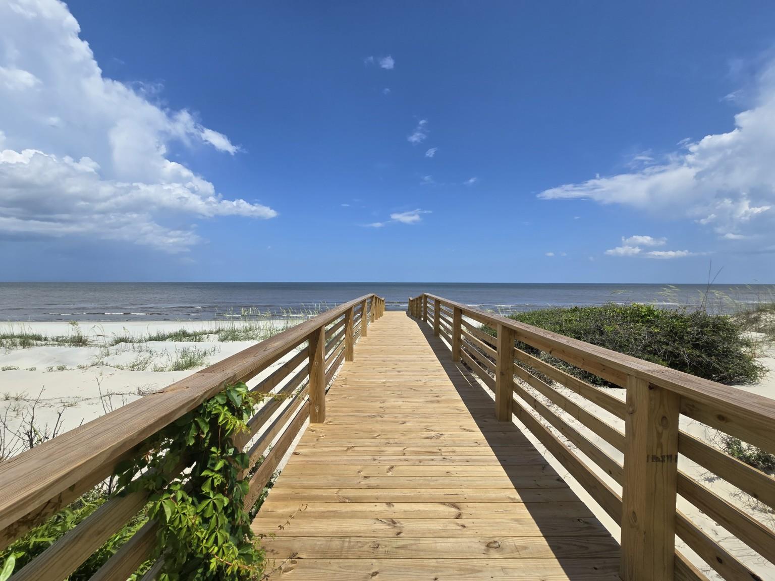 Follow the Seaside Retreat boardwalk over the dunes for direct beach access from this oceanfront Jekyll Island vacation home.