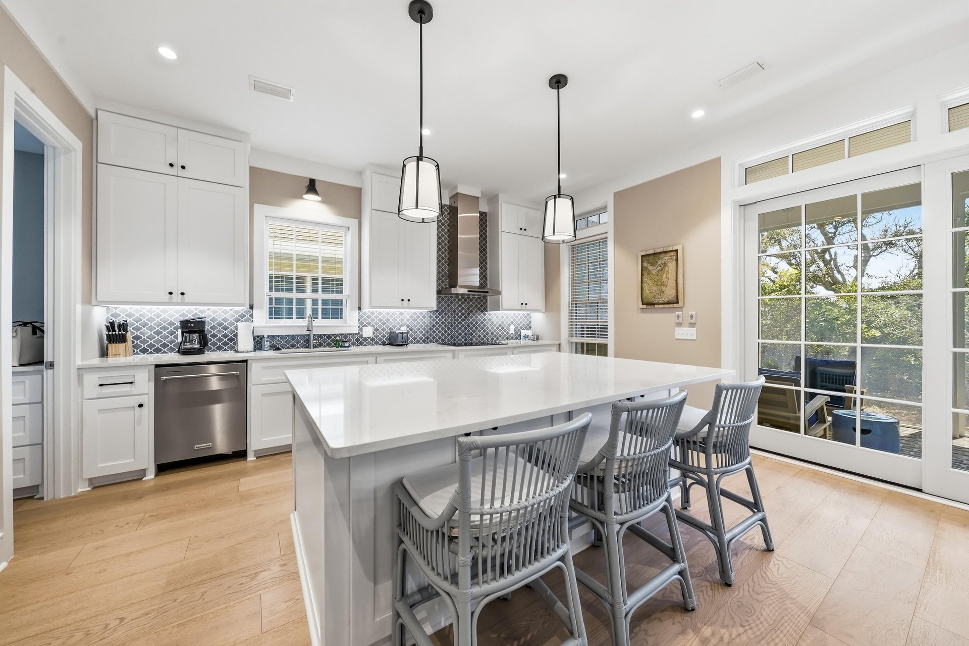A long quartz island anchors the kitchen with plenty of prep space, casual seating and doors to outdoor dining.