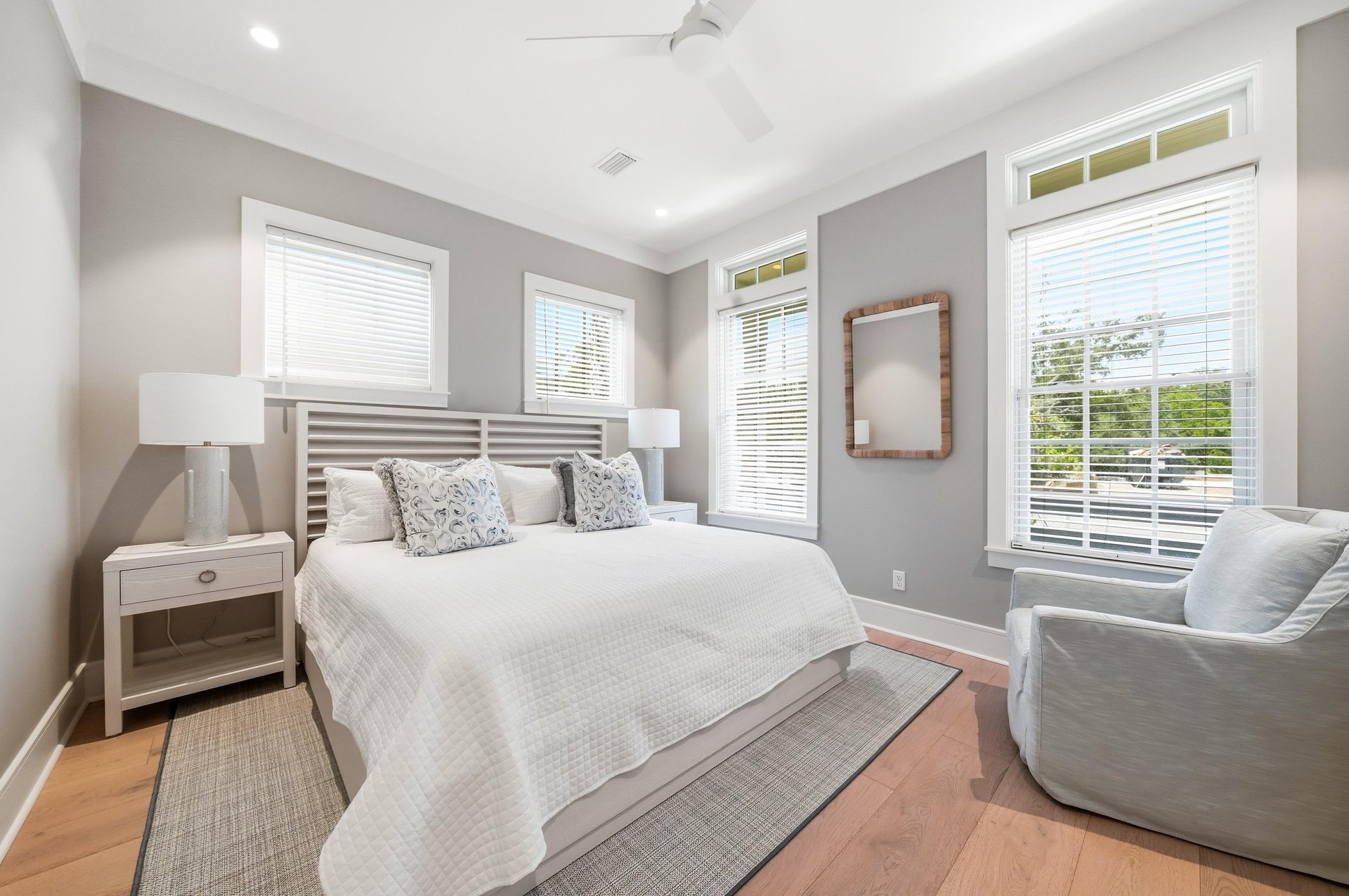 The only bedroom on the main level pairs a king bed with an attached bath, dressing area and bright coastal light.