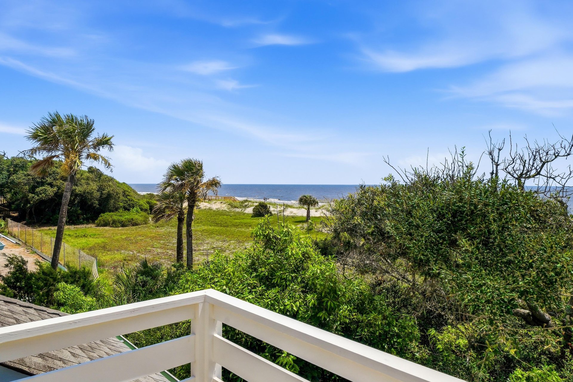 The upstairs balcony looks over native coastal landscape to the water beyond.