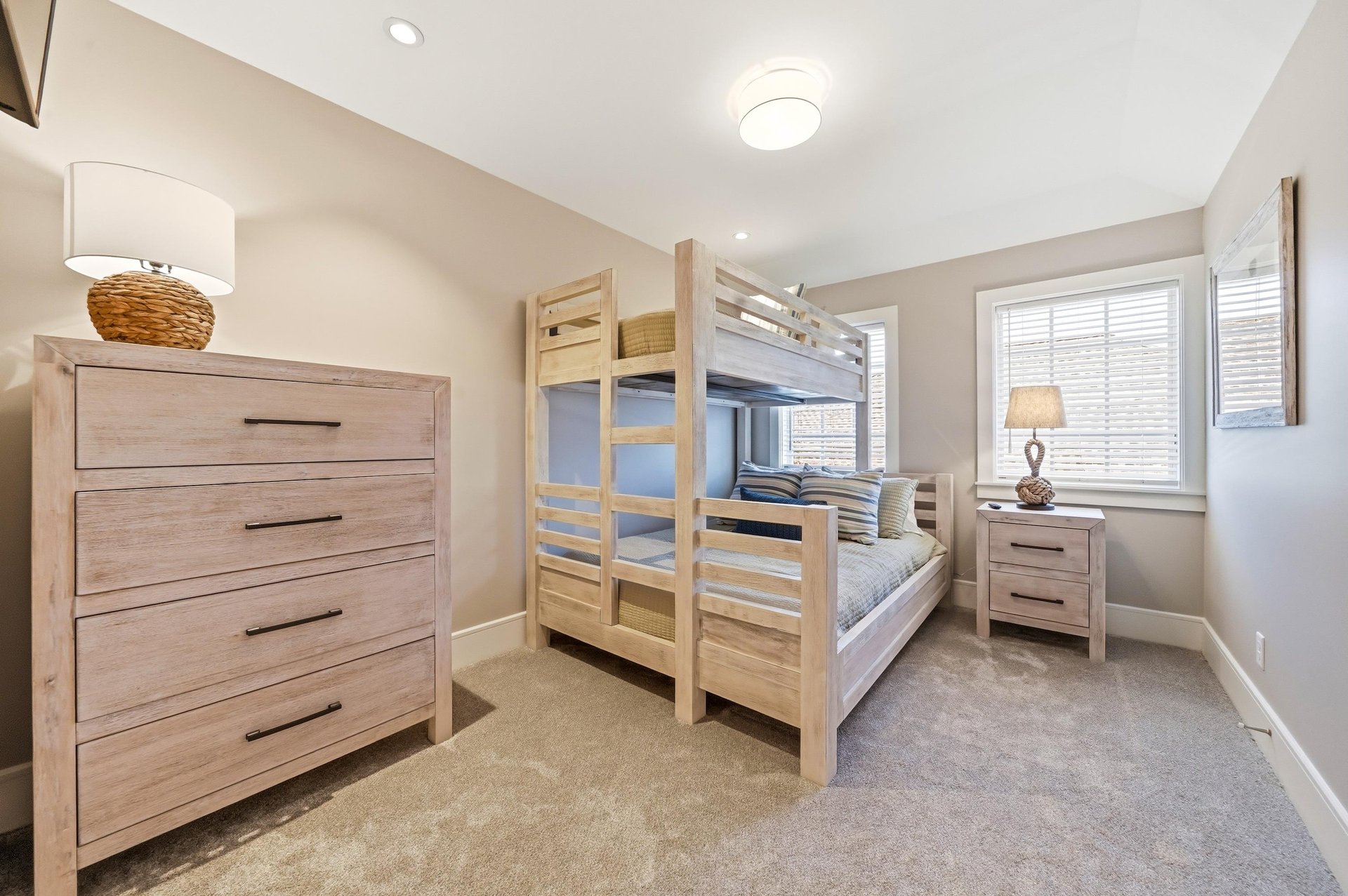 The upstairs bunk room sleeps three with a queen below, twin above, dresser and wallmounted TV.