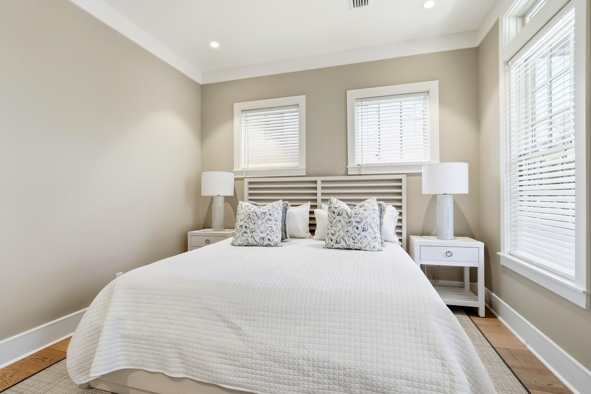 A straightforward bed view shows the generous scale of the suite, nightstands and windows on two walls.