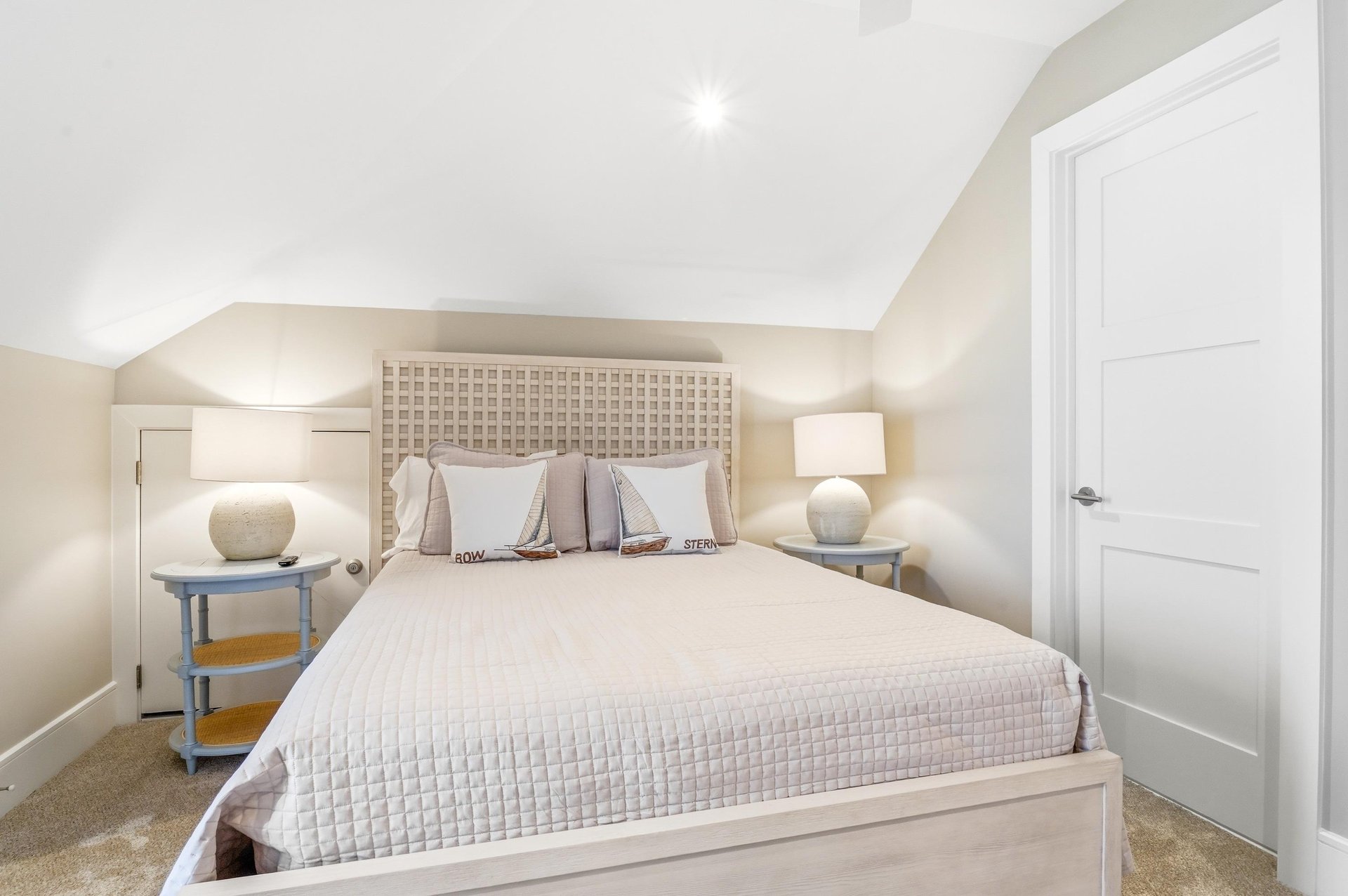 A centered bed view shows the calm proportions of the room and easy access to a full bath nearby.