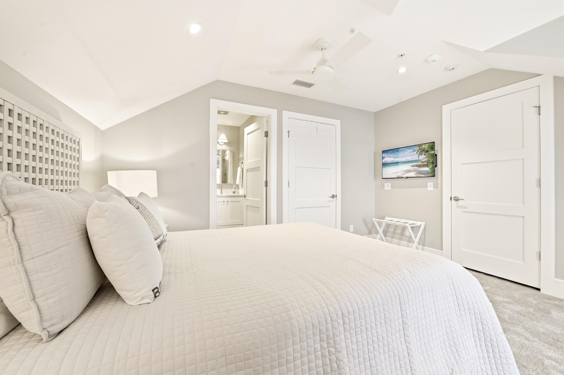 A wallmounted TV, nearby full bath and balcony access round out this upstairs bedroom.