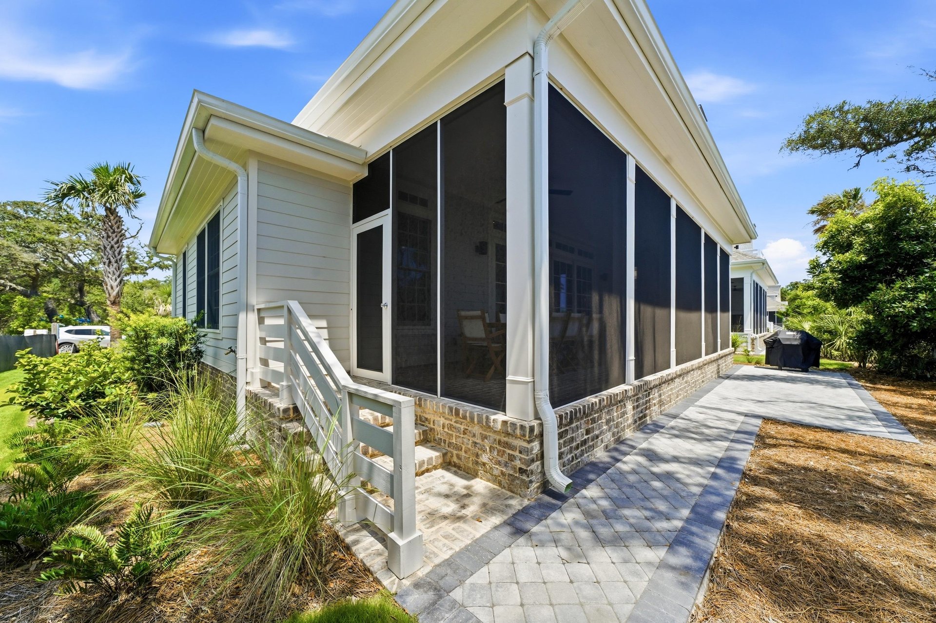 The side view shows the full depth of the porch and the paved route around the home.