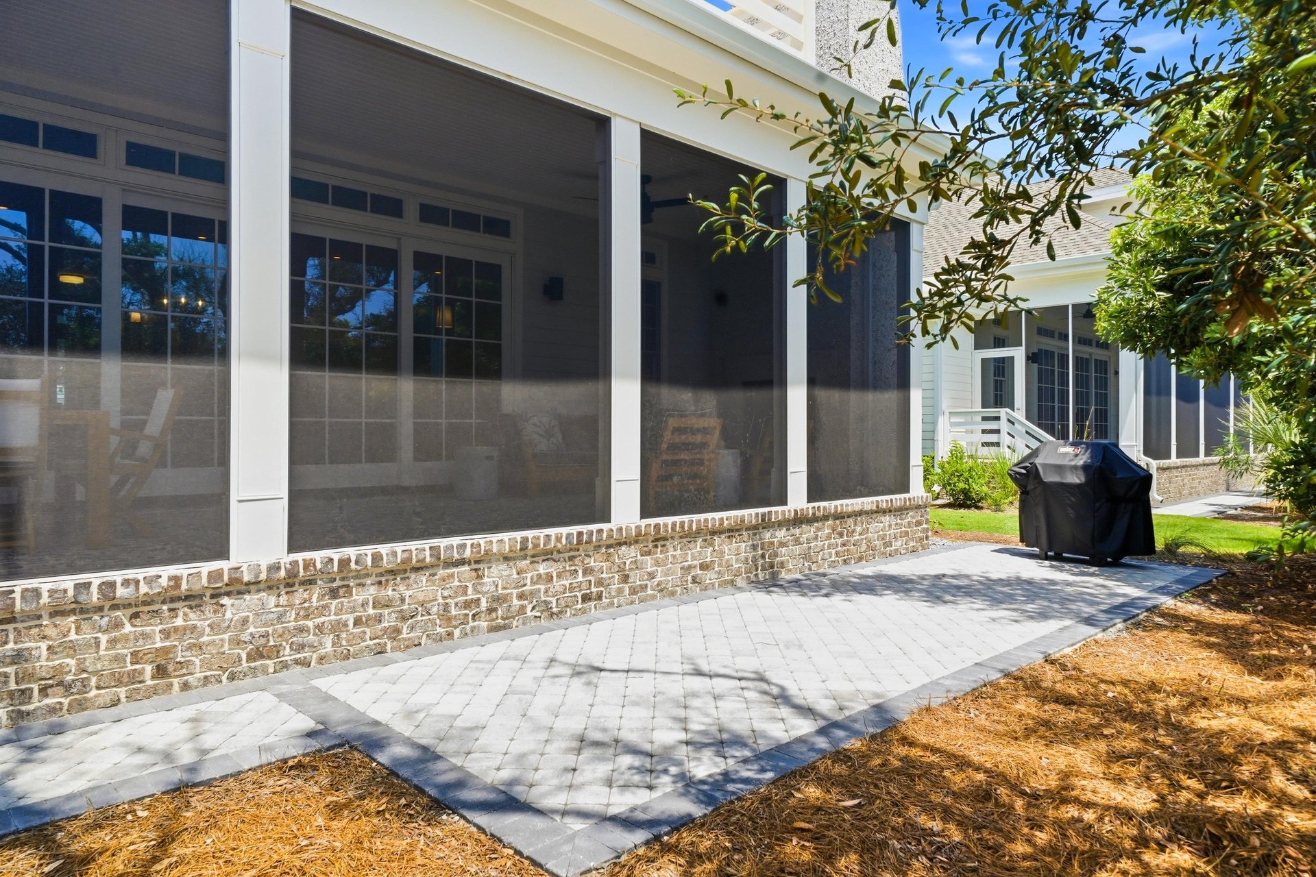The grill sits on the paver patio just outside the covered outdoor dining and lounge areas.