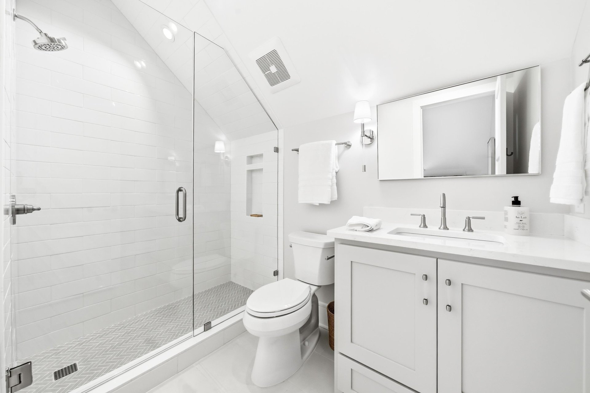 A glass shower, single vanity and chrome fixtures furnish this bathroom.