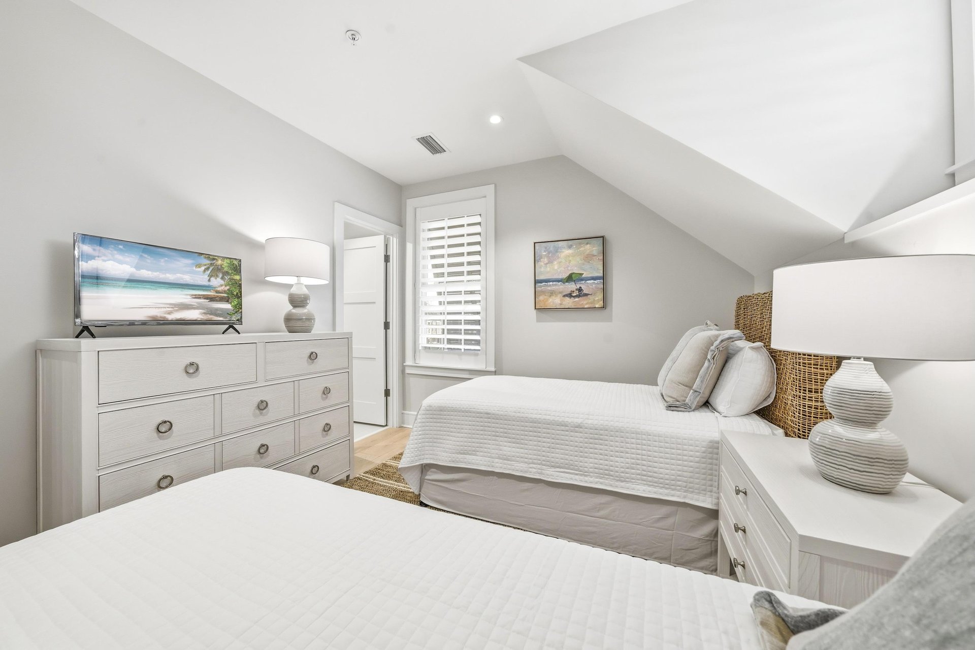 A dresser and television face the two beds.