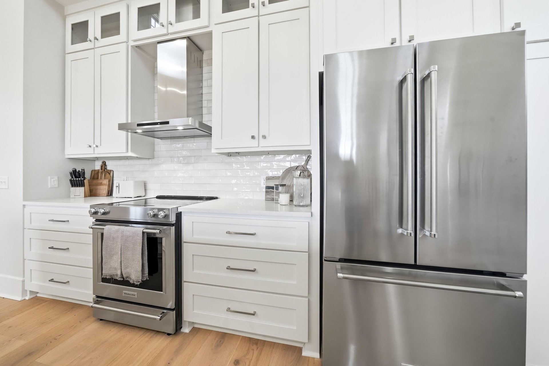 A Frenchdoor refrigerator and range sit beneath tall white cabinetry.