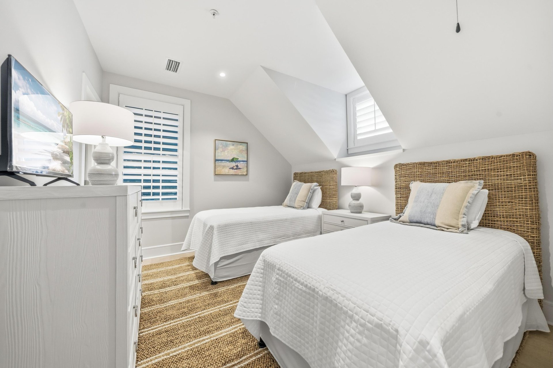 Two separate twin beds have woven headboards beneath the sloped ceiling.