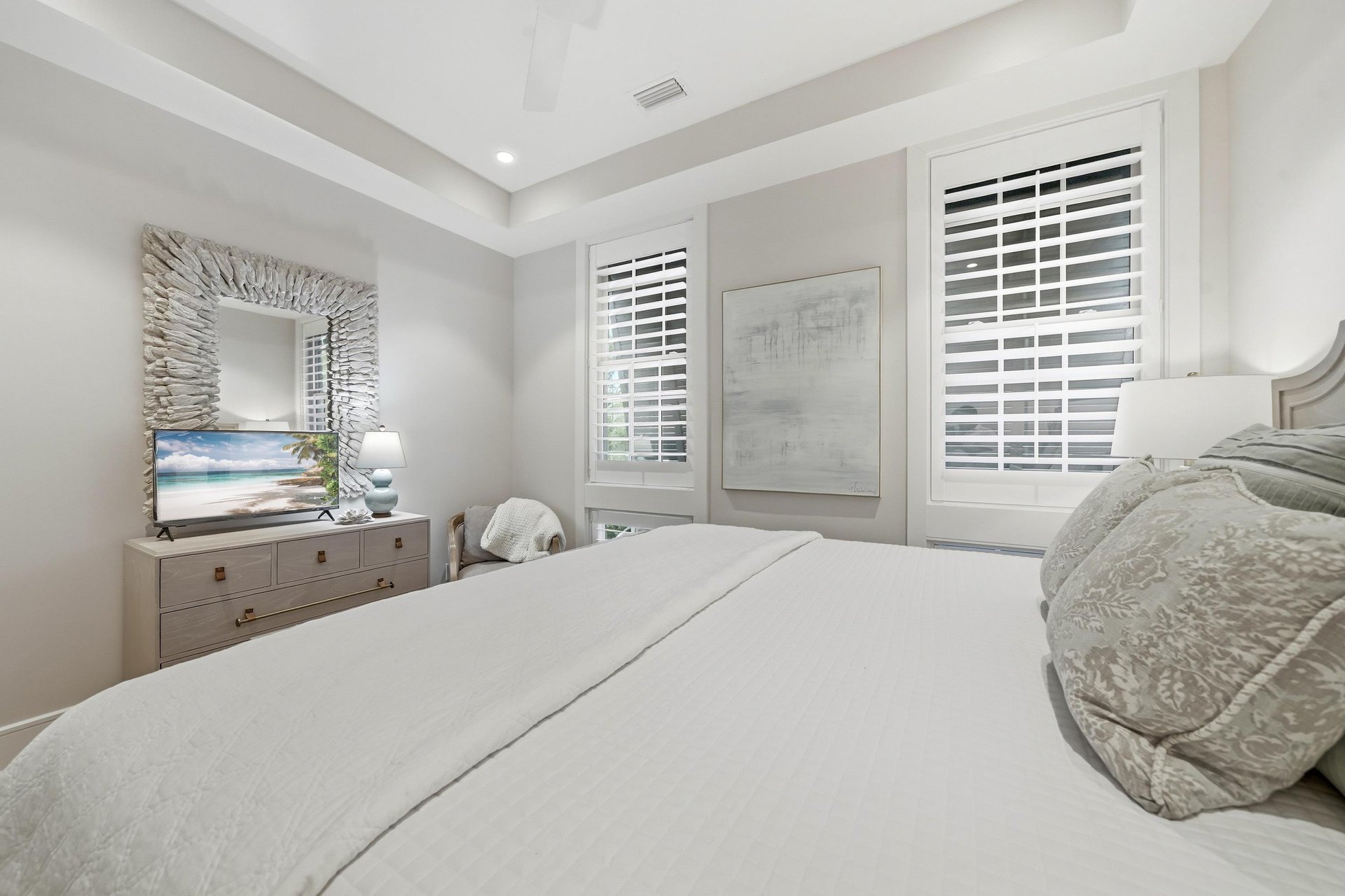 A matching dresser and shuttered windows face the bed.