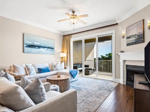 Unwind in the elegant living room with plush seating, coastal artwork, and a cozy fireplace. Step onto your private balcony for peaceful views.