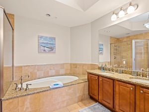 Unwind in your private bathroom oasis with a soaking tub and granite vanity, where coastal artwork sets a serene mood.
