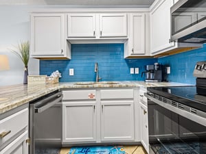 Fully equipped kitchen awaits with vibrant blue tile, marble countertops, and everything you need for memorable meals together.