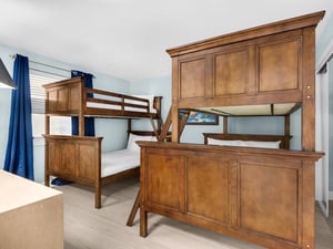 Spacious bunk room with custombuilt wooden beds perfect for family getaways, featuring ample storage and cheerful blue accents throughout your stay.