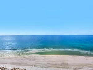 Pristine beach with crystalclear turquoise waters and soft sand stretches endlessly along the coastline under brilliant blue skies.
