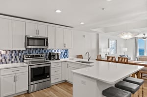 Your spacious kitchen features sleek white cabinets, modern appliances, and a breakfast bar perfect for morning coffee or casual dining.