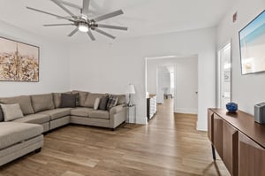 Relax in your spacious living room featuring modern furnishings, gleaming hardwood floors, and a cooling ceiling fan for ultimate comfort.