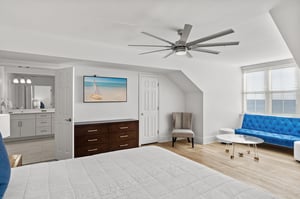 Relax in your spacious king master suite featuring a vibrant blue sofa, coastal artwork, and an ensuite bathroom for ultimate comfort.