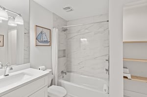 Relax in your pristine 2nd floor shared bathroom featuring elegant marblelook tiles, a soaking tub, and thoughtful nautical touches that create a spalike retreat.