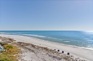 Pristine white sand beach stretches endlessly along crystalclear emerald waters with gentle waves rolling to shore.