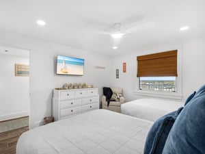 Unwind in your bright bedroom with two cozy beds, modern TV, and stunning window views that frame the perfect escape.