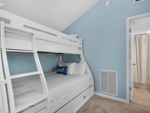 Cozy bunk room with crisp white linens and soothing blue walls creates your perfect beach retreat sleeping space.