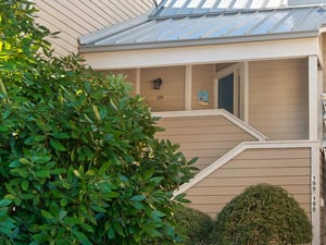 Charming coastal cottage entrance with covered porch and mature landscaping creates a welcoming arrival experience.