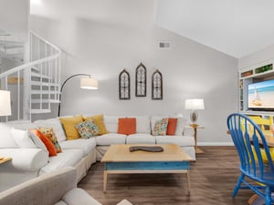 Sink into your spacious sectional sofa and unwind in this bright, airy living room with soaring ceilings and vibrant coastal touches.