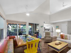 Relax in this bright, open living space where colorful dining chairs and cozy seating create the perfect spot for family meals and game nights.