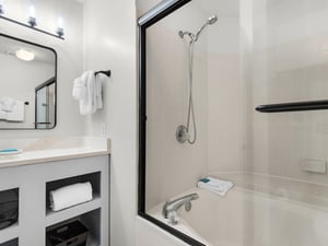 Step into your pristine bathroom with modern amenities and fresh towels waiting for your arrival.
