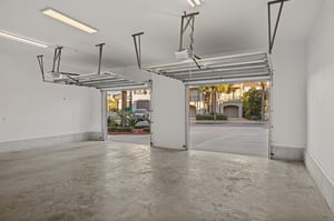 Spacious twocar garage with automatic doors opens to a quiet residential street lined with elegant homes and mature landscaping.