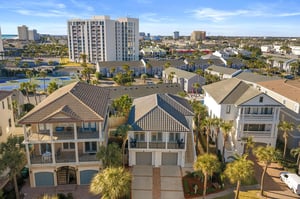 Aerial view of coastal residential properties with palm trees and city skyline in a vibrant beachside community.