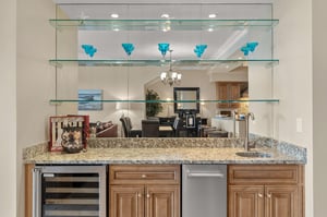 Entertain in style at your private bar with granite counters, wine chiller, ice maker, and elegant glass display shelving.
