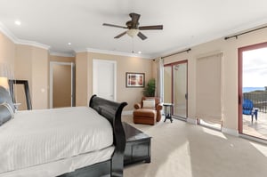 Relax in your spacious bedroom with plush carpeting, ceiling fan, and private balcony access offering peaceful outdoor views.